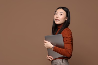 Photo of Portrait of smiling woman with laptop on brown background. Space for text