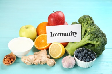 Photo of Card with word Immunity and fresh products on light blue wooden table