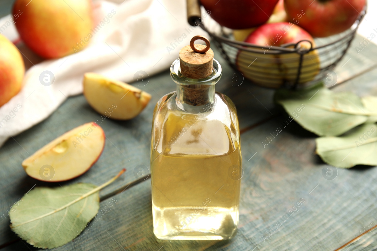 Photo of Natural apple vinegar and fresh fruits on blue wooden table