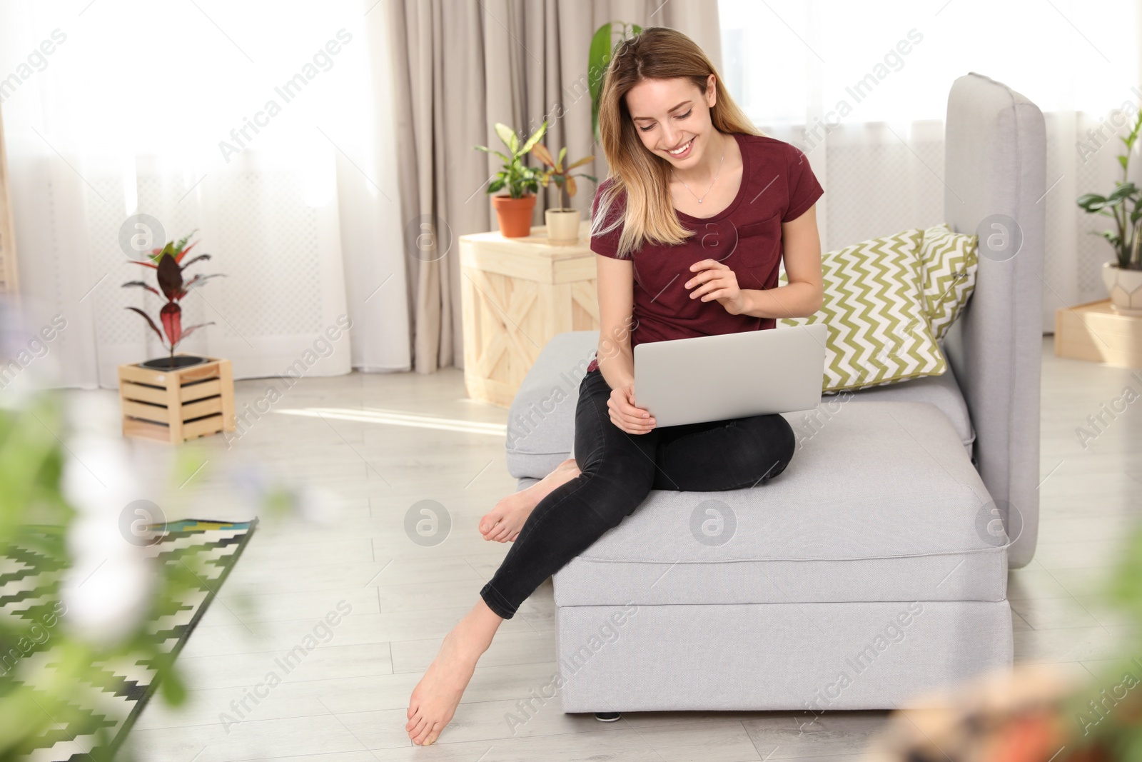 Photo of Young woman using laptop at home, space for text. Trendy room interior with plants