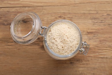 Photo of Glass jar with brewer`s yeast flakes on wooden table, top view