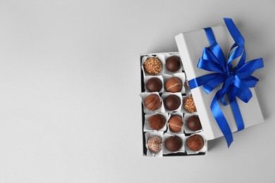 Photo of Box with delicious chocolate candies on beige background, top view. Space for text