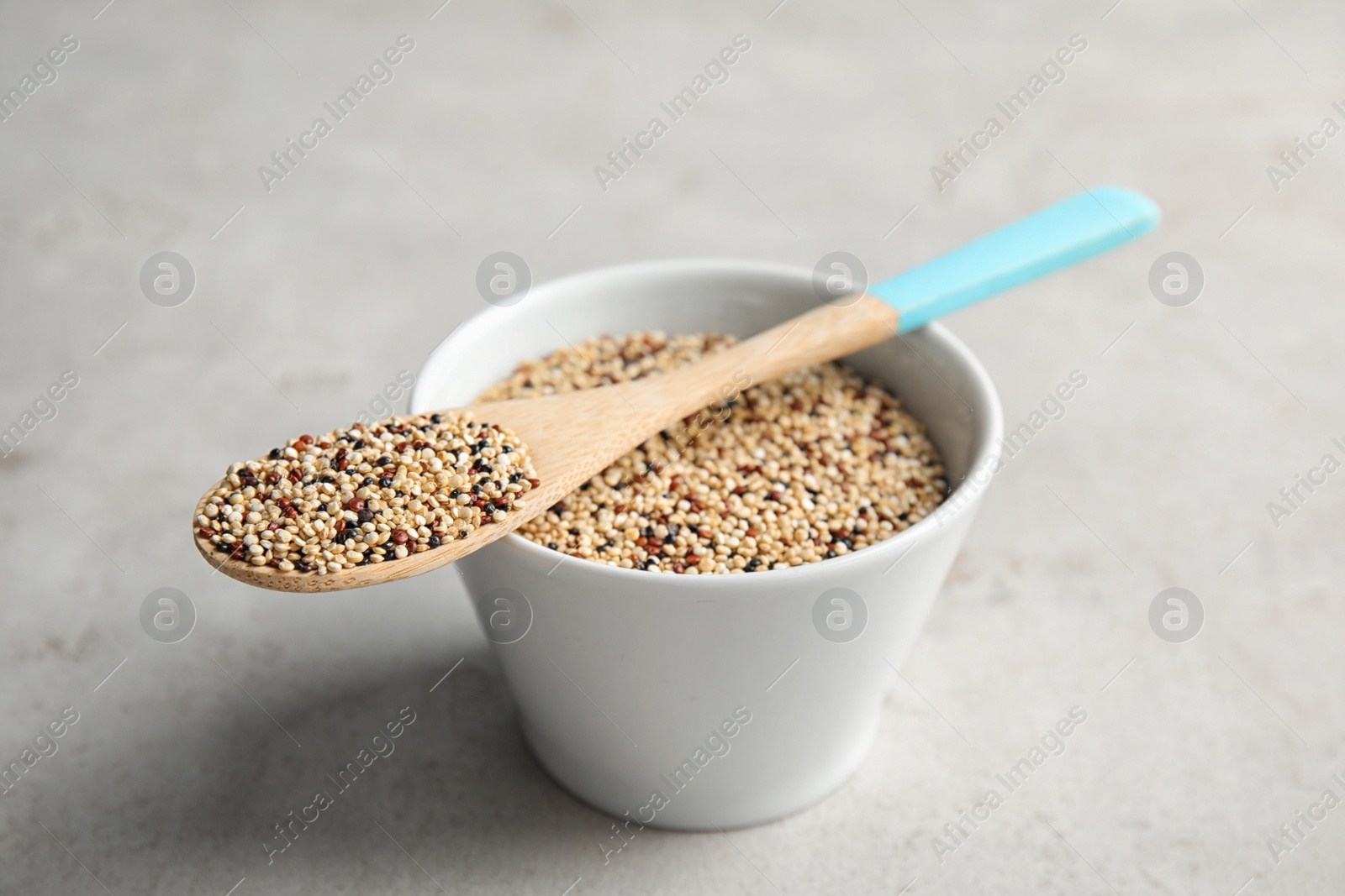 Photo of Bowl and spoon with mixed quinoa seeds on grey background