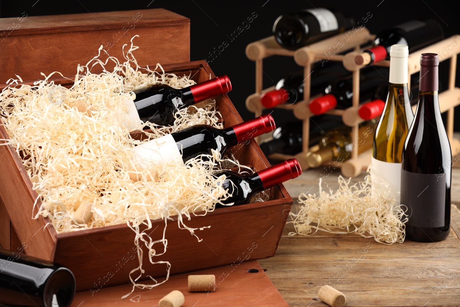 Photo of Box with wine bottles on wooden table against black background