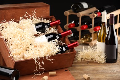 Photo of Box with wine bottles on wooden table against black background