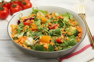 Photo of Delicious salad with lentils and vegetables served on white wooden table