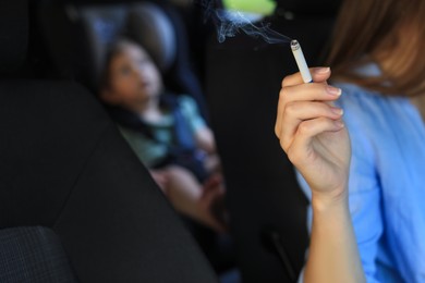 Photo of Mother with cigarette and child in car, closeup. Don't smoke near kids