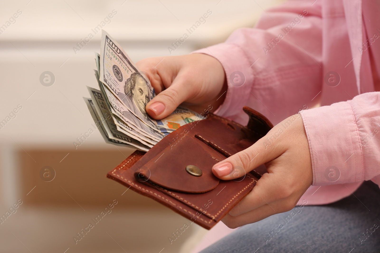 Photo of Woman counting dollar bills indoors, closeup. Money exchange