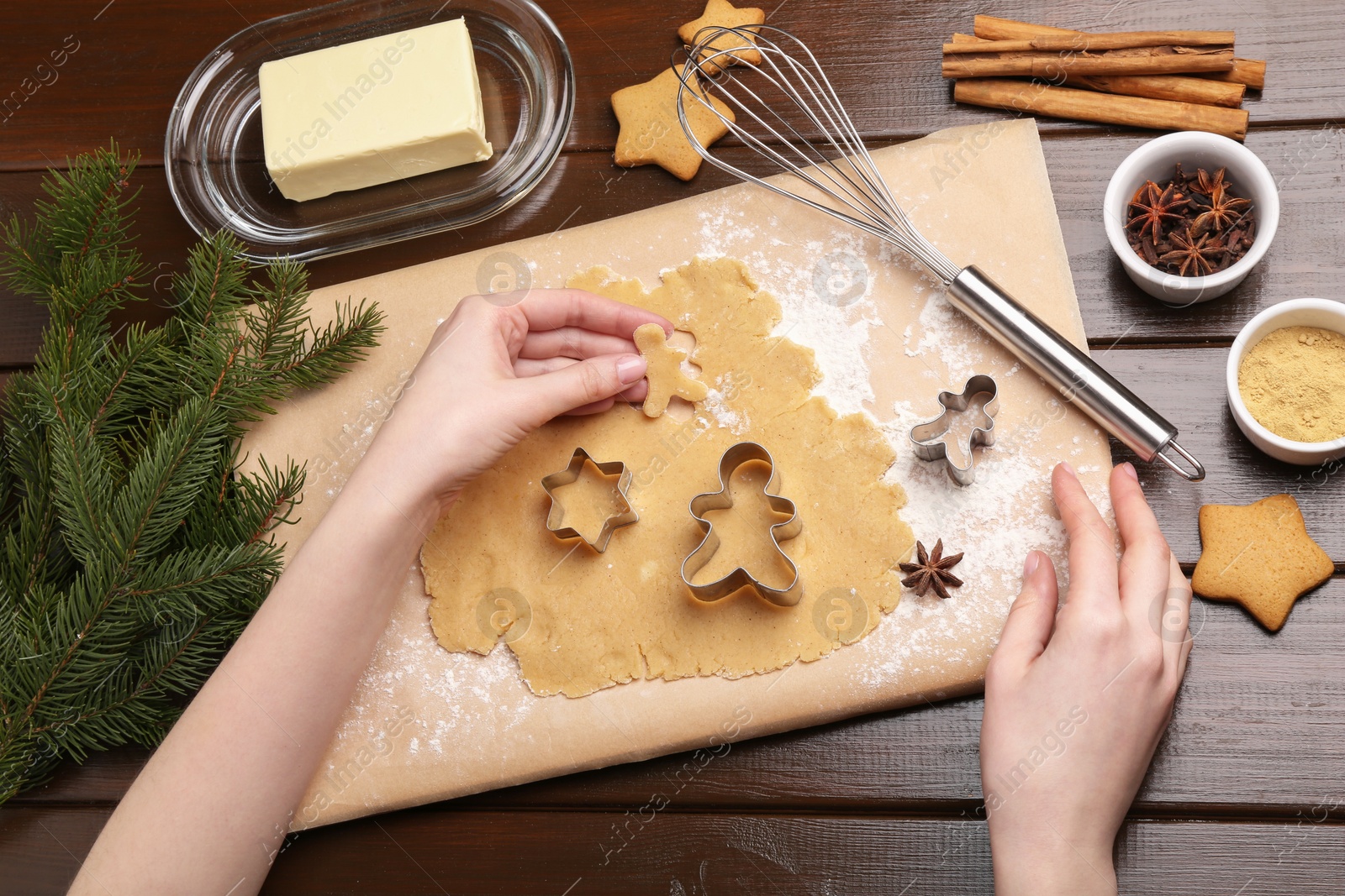 Photo of Woman making Christmas cookies with cutters at wooden table, top view