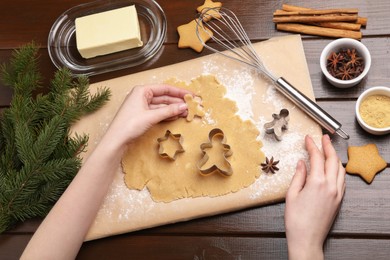 Photo of Woman making Christmas cookies with cutters at wooden table, top view