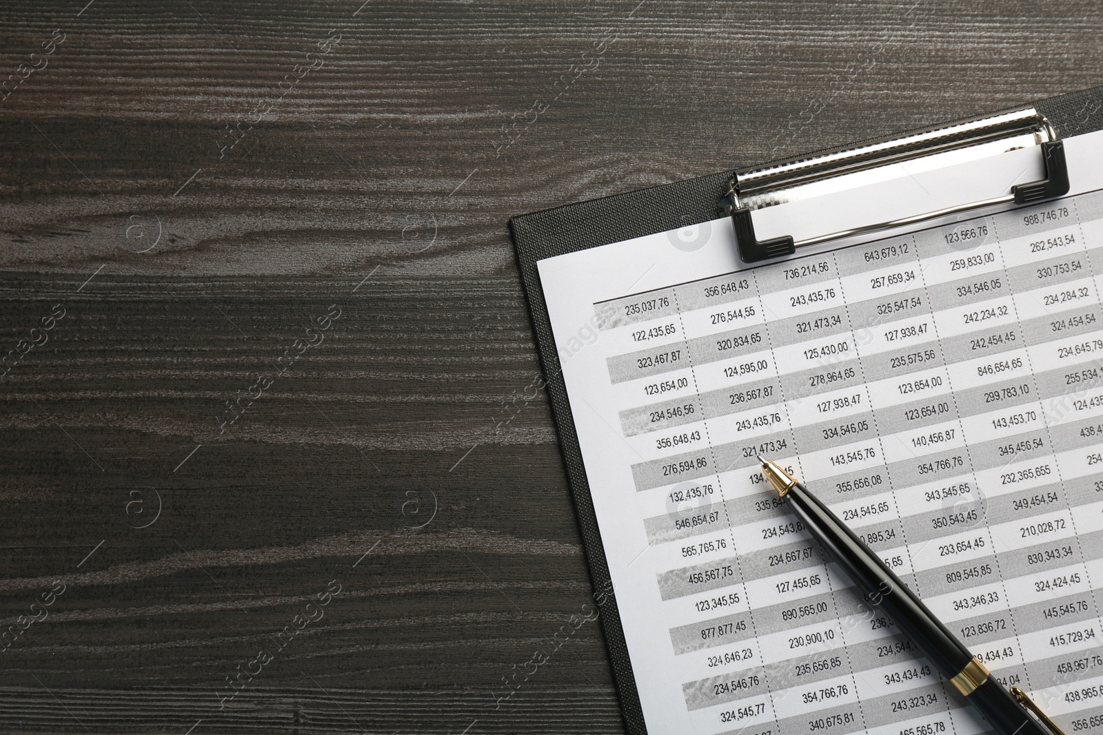 Photo of Clipboard with accounting document and pen on wooden table, top view. Space for text