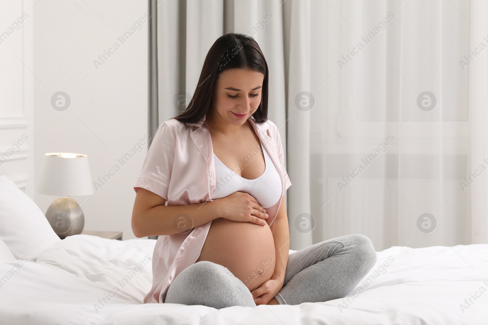 Photo of Beautiful pregnant woman on bed at home