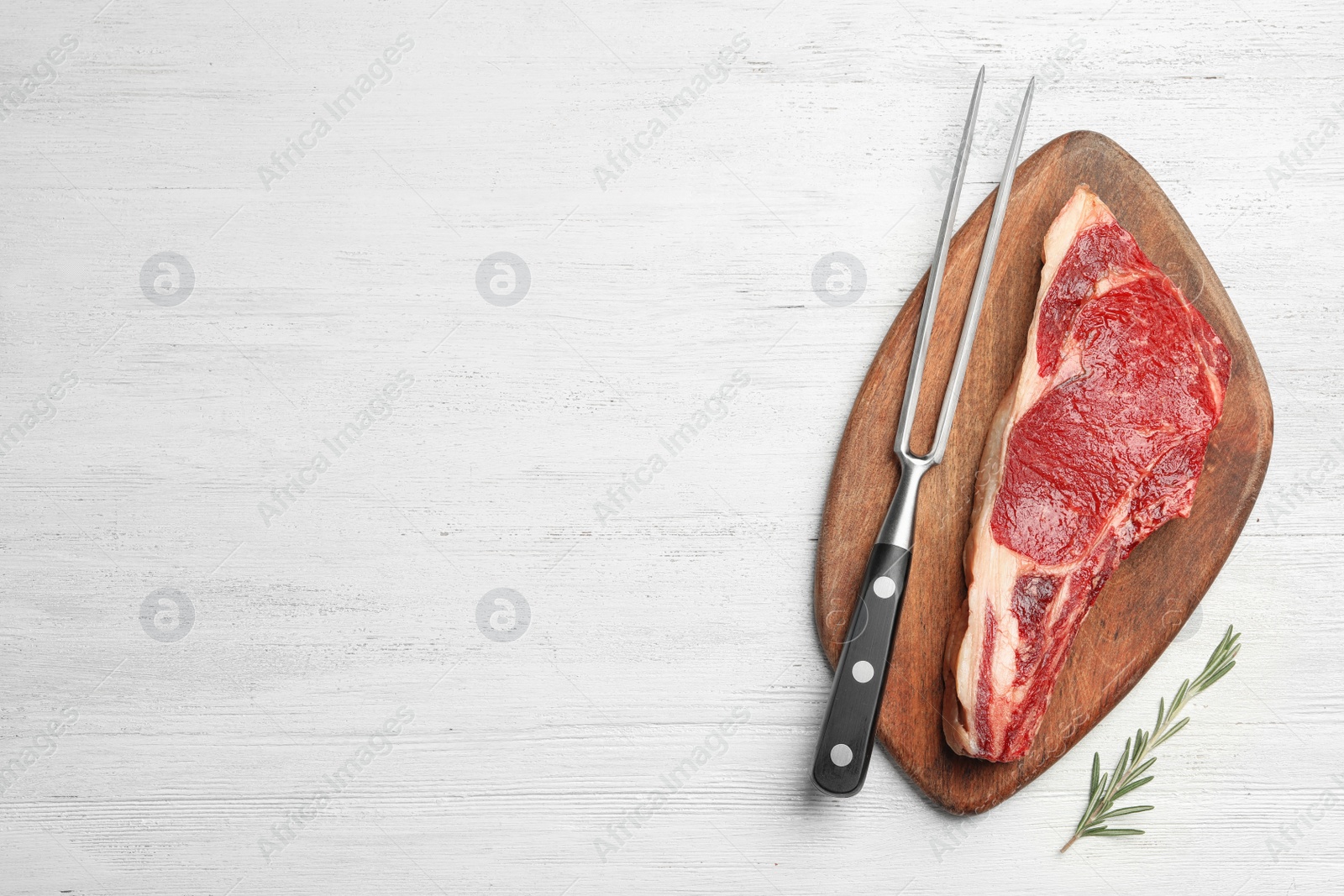 Photo of Fresh raw beef meat and fork on white wooden table, flat lay. Space for text