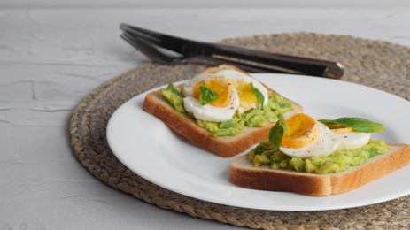 Photo of Tasty sandwiches with boiled egg, avocado and spinach served on white textured table, closeup