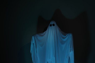 Creepy ghost. Woman covered with sheet on dark background