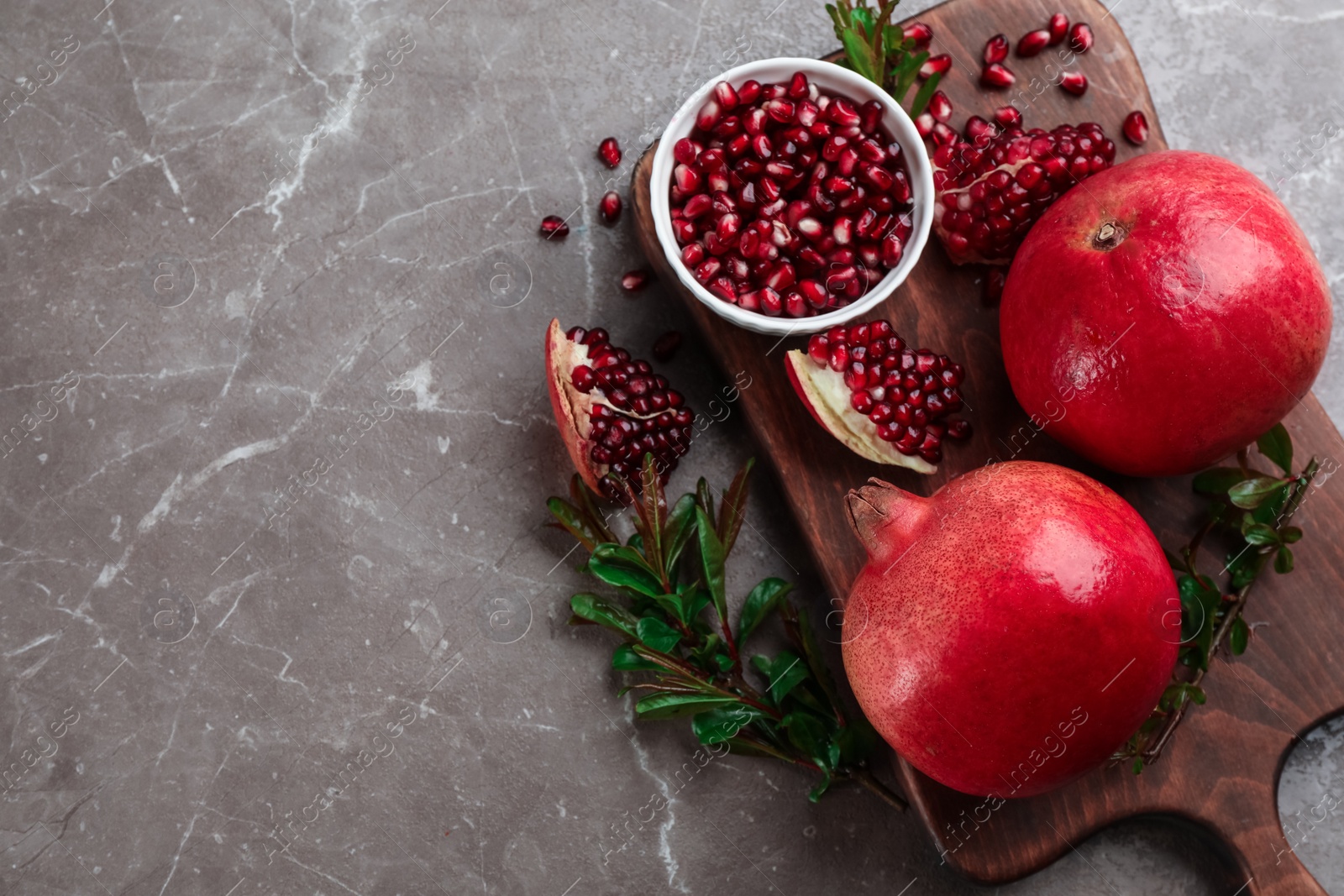 Photo of Delicious ripe pomegranates on grey table, flat lay. Space for text