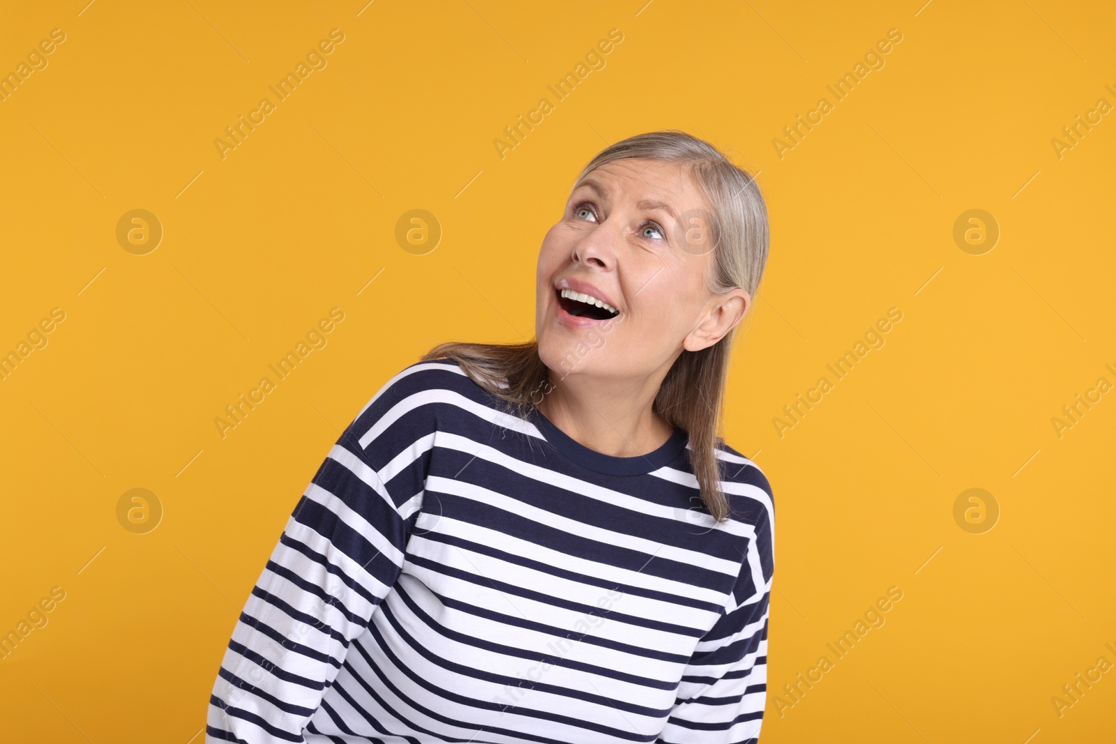 Photo of Portrait of surprised senior woman on yellow background