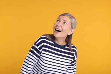 Portrait of surprised senior woman on yellow background