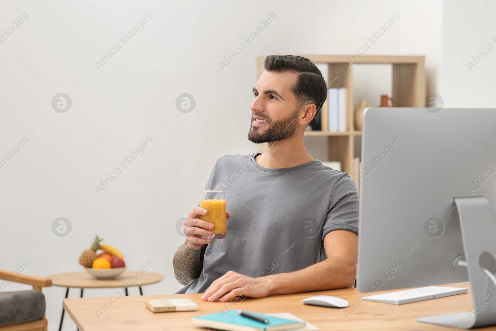 Photo of Handsome man with delicious smoothie at workplace in office. Space for text