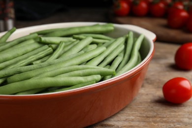 Raw green beans in baking dish on wooden table, closeup