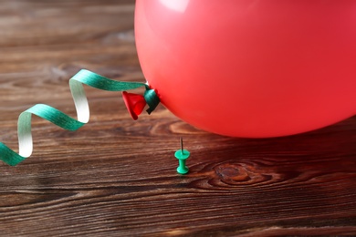 Color balloon and pin on wooden background, closeup