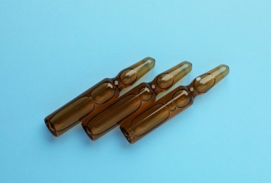 Photo of Medical ampoules with solution on light blue background, flat lay