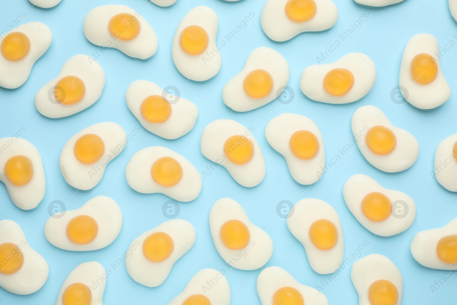 Photo of Tasty jelly candies in shape of egg on light blue background, flat lay