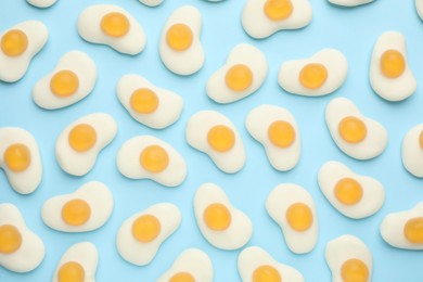 Photo of Tasty jelly candies in shape of egg on light blue background, flat lay