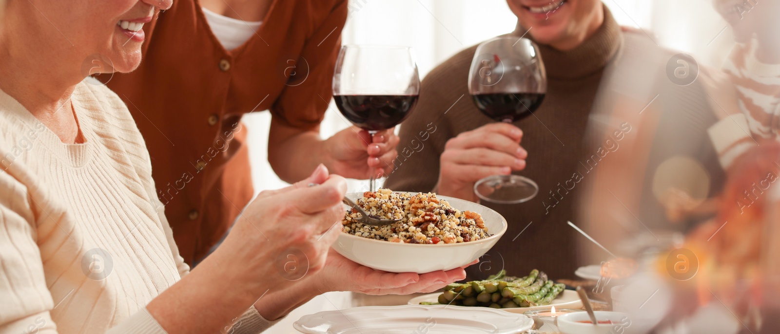 Image of Woman with bowl of traditional Christmas slavic dish kutia and her family at festive dinner. Banner design