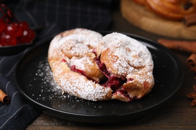Delicious buns with berries and sugar powder on wooden table, closeup