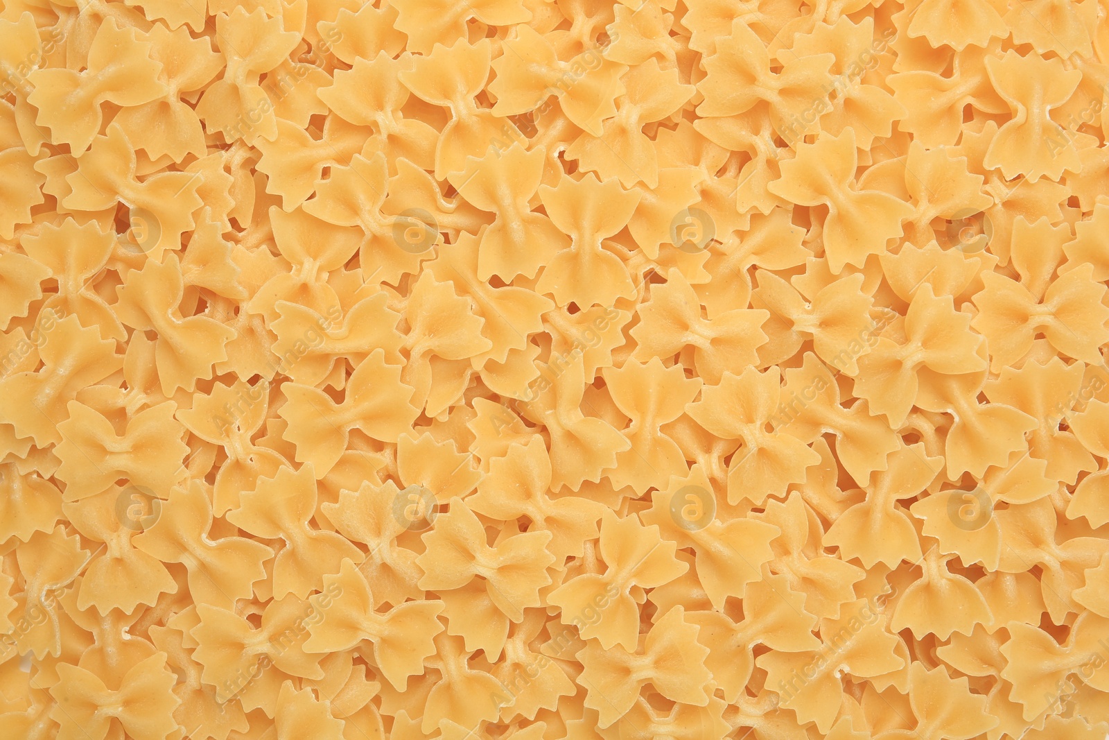 Photo of Raw farfalle pasta as background, top view