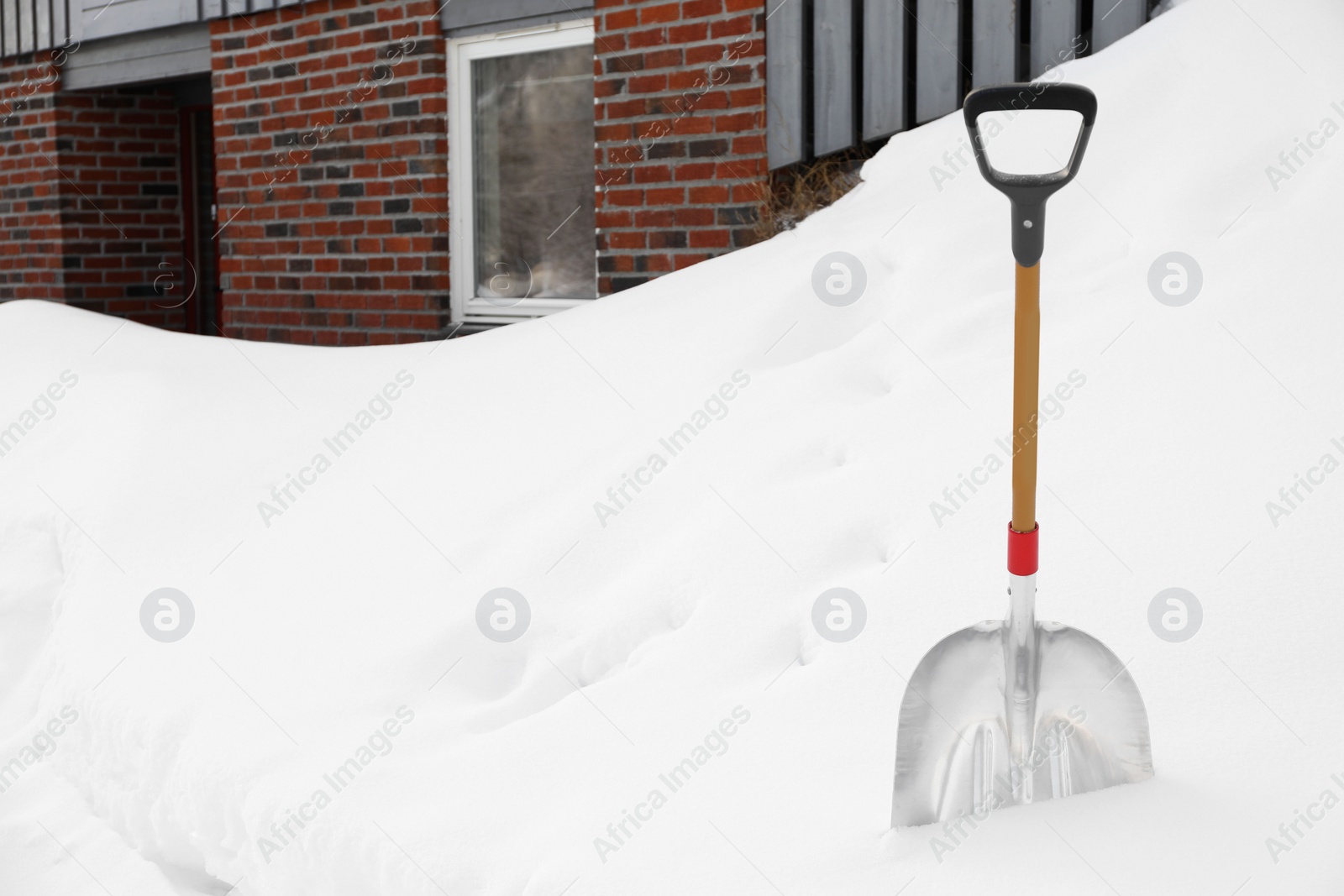 Photo of Metal shovel in large snowbank on winter day