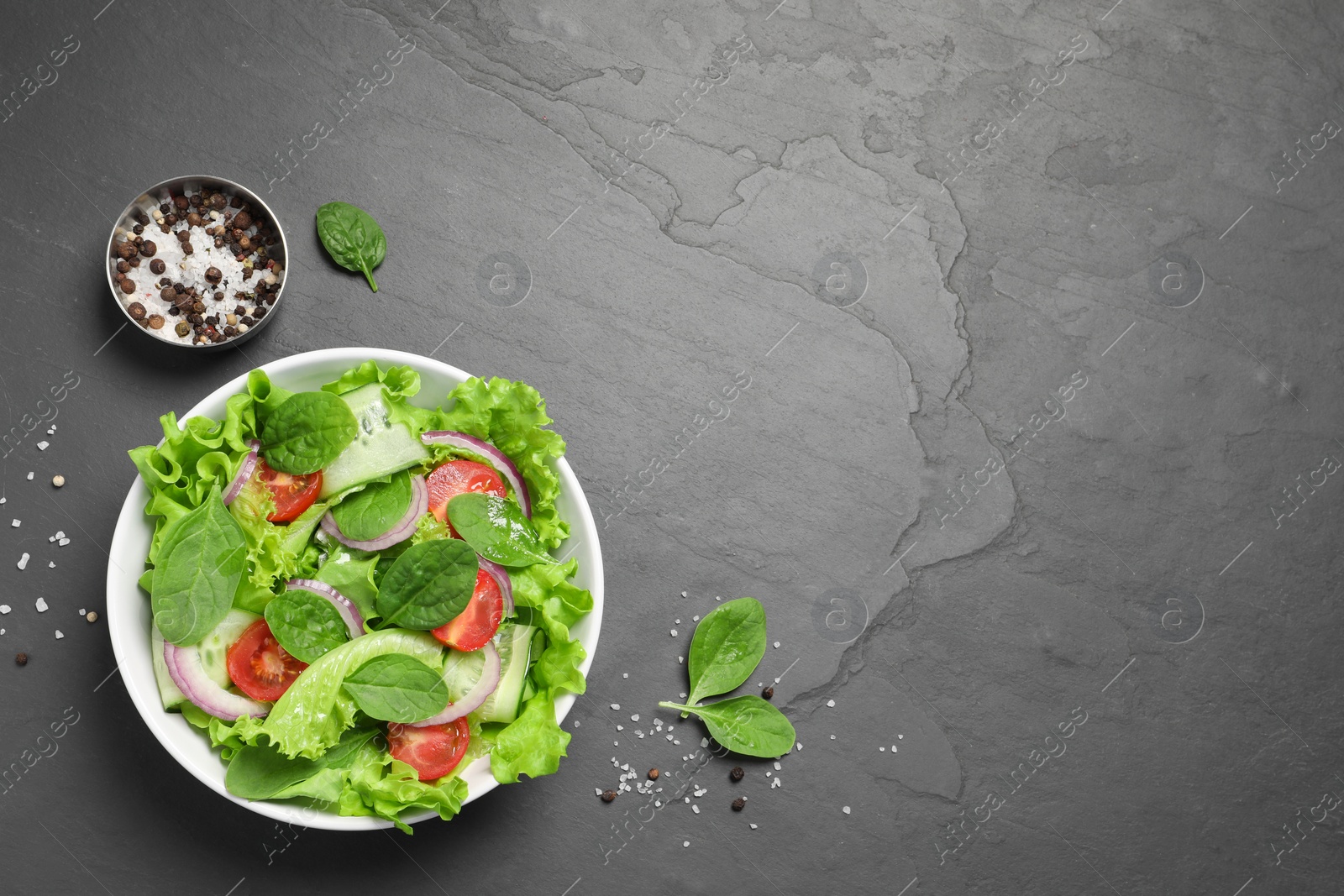 Photo of Delicious vegetable salad, salt and pepper on grey table, flat lay. Space for text