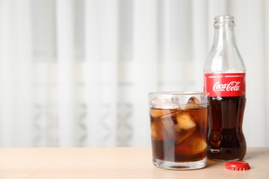 MYKOLAIV, UKRAINE - NOVEMBER 15, 2018: Glass and bottle with Coca Cola on table indoors. Space for text