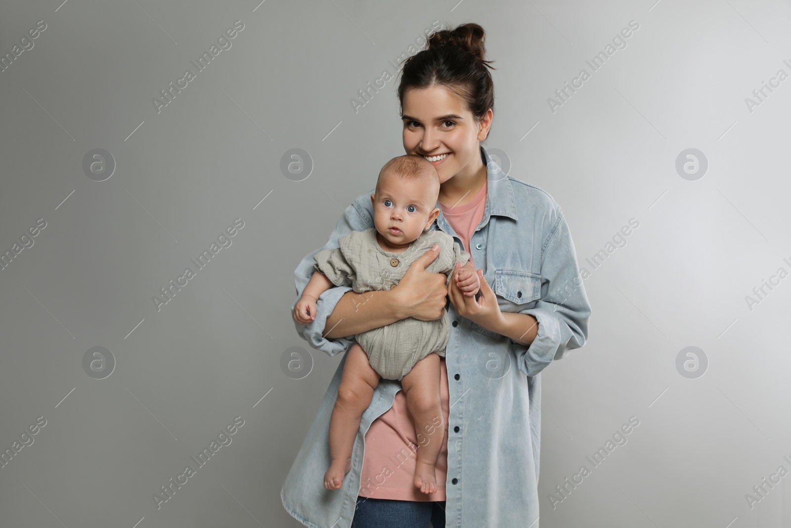 Photo of Beautiful mother with her cute baby on grey background. Space for text