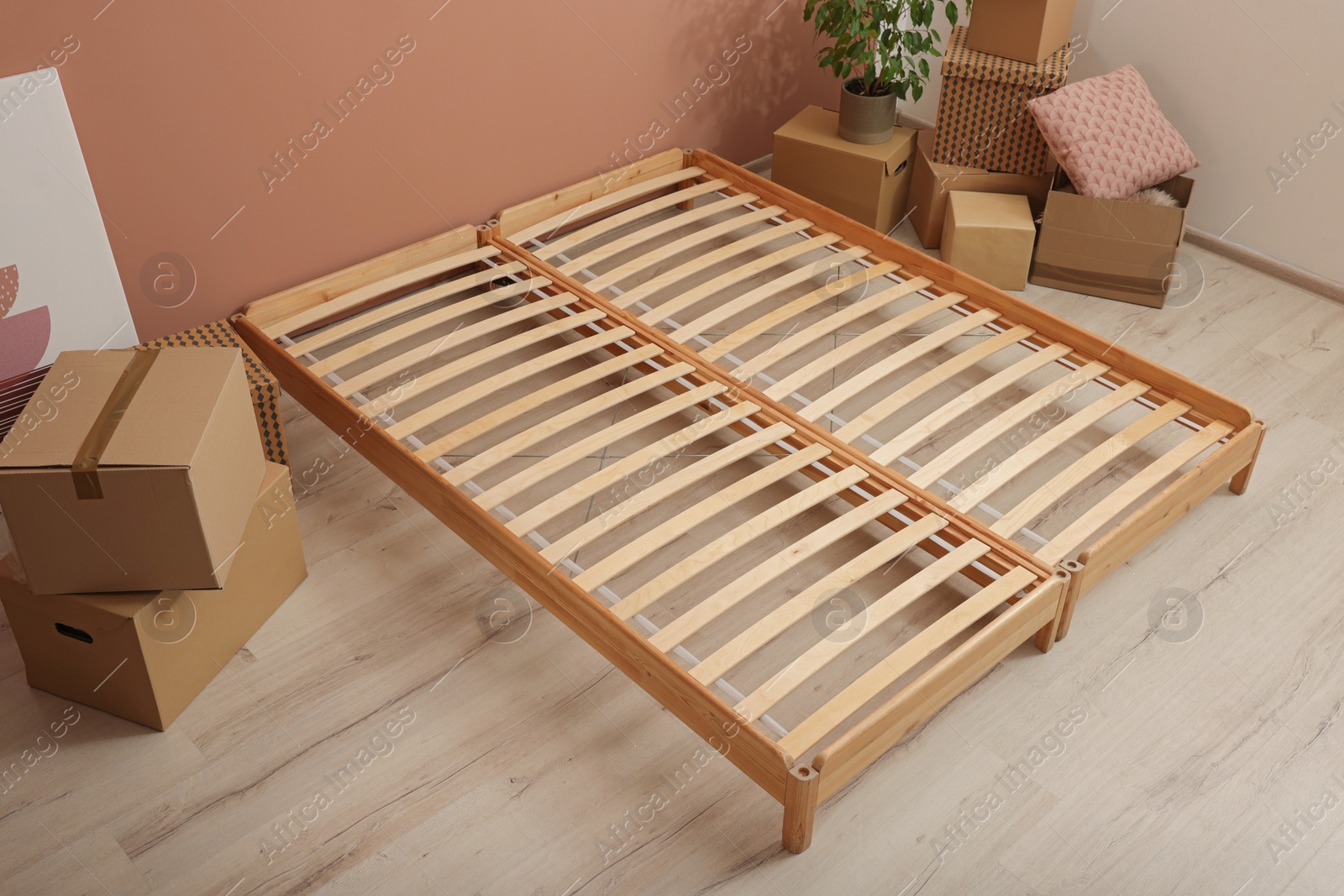 Photo of Wooden bed frame and cardboard boxes on floor in room