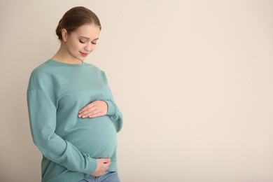 Photo of Young pregnant woman on beige background. Space for text