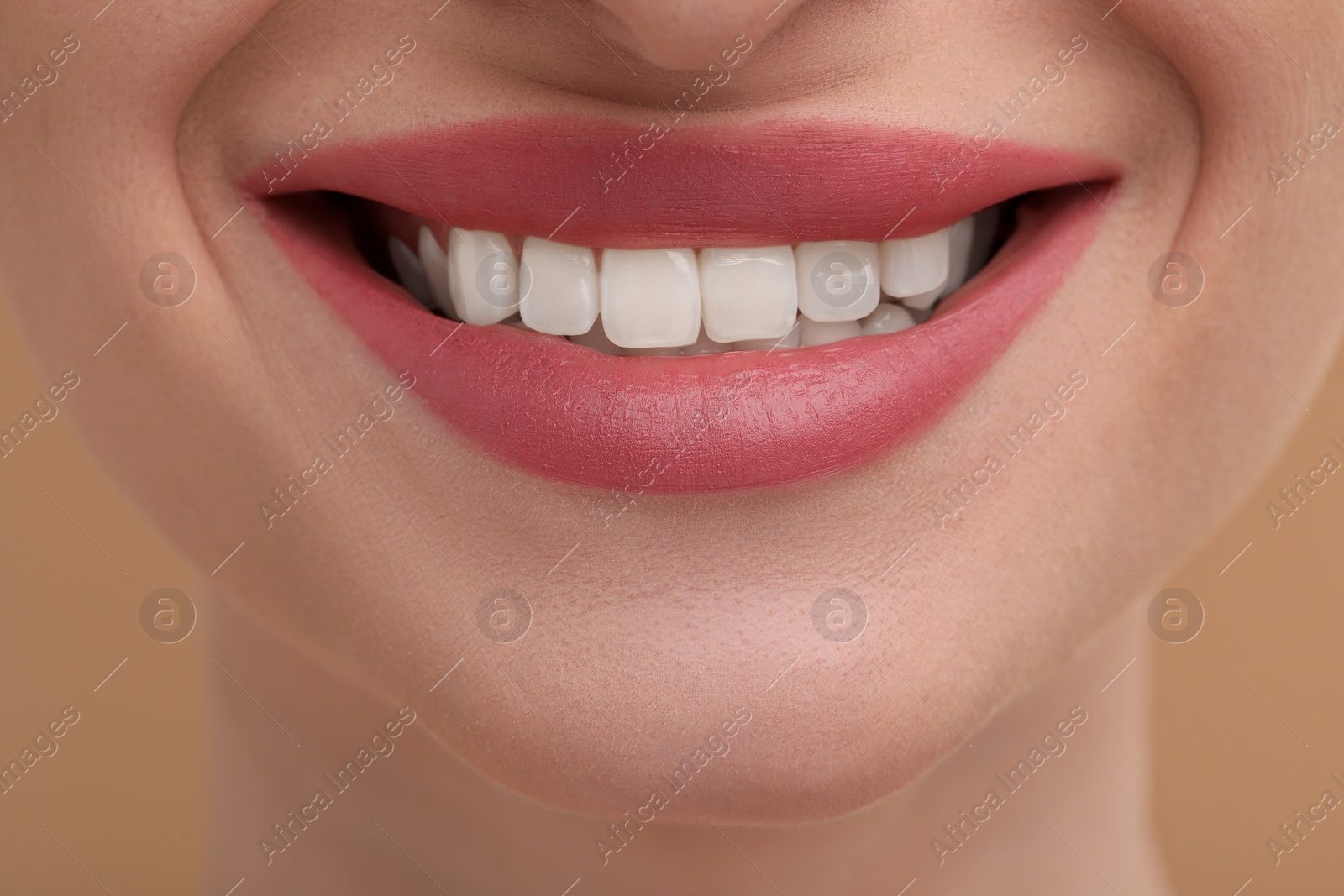 Photo of Young woman with beautiful smile on beige background, closeup