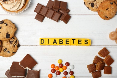 Photo of Flat lay composition with word "Diabetes" and sweets on wooden background