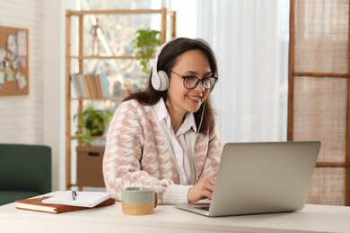 Photo of Woman with modern laptop and headphones learning at home