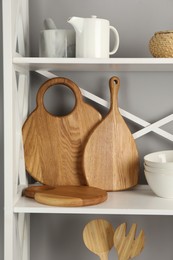 Photo of Wooden cutting boards and kitchen utensils on shelving unit