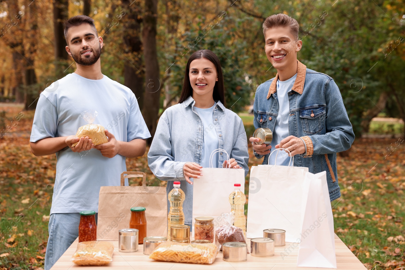 Photo of Portrait of volunteers packing food products at table in park