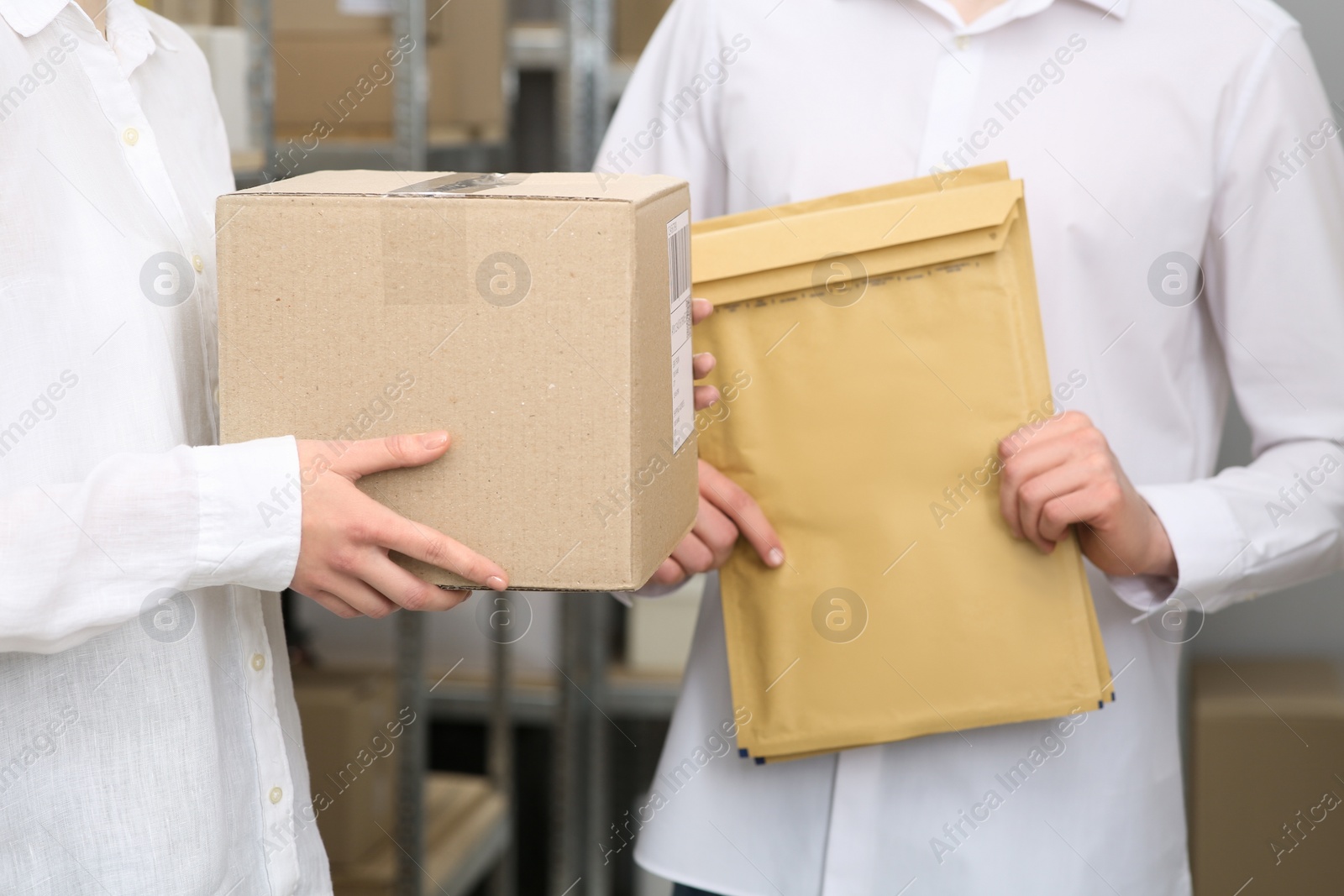 Photo of Post office workers with parcels near rack indoors, closeup