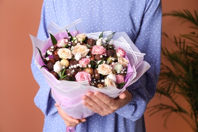 Woman with beautiful food bouquet on brown background, closeup