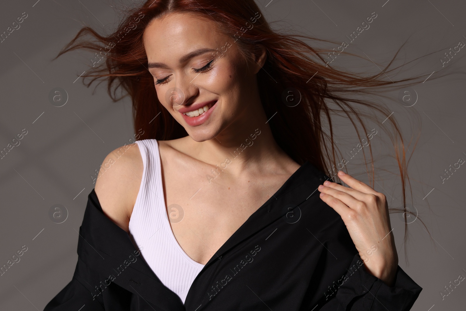 Photo of Beautiful young woman in black shirt on gray background