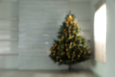 Photo of Blurred view of Christmas tree in empty room, space for text. Bokeh effect