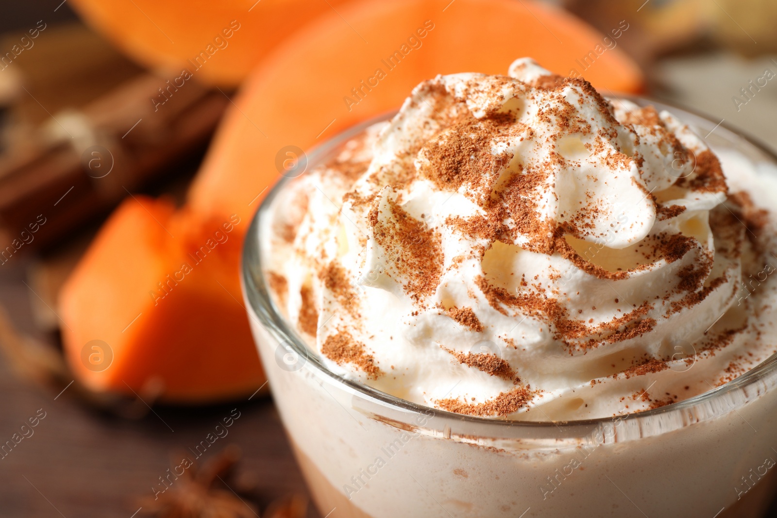 Photo of Delicious pumpkin latte with whipped cream on table, closeup