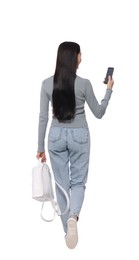 Young woman using smartphone while walking on white background, back view