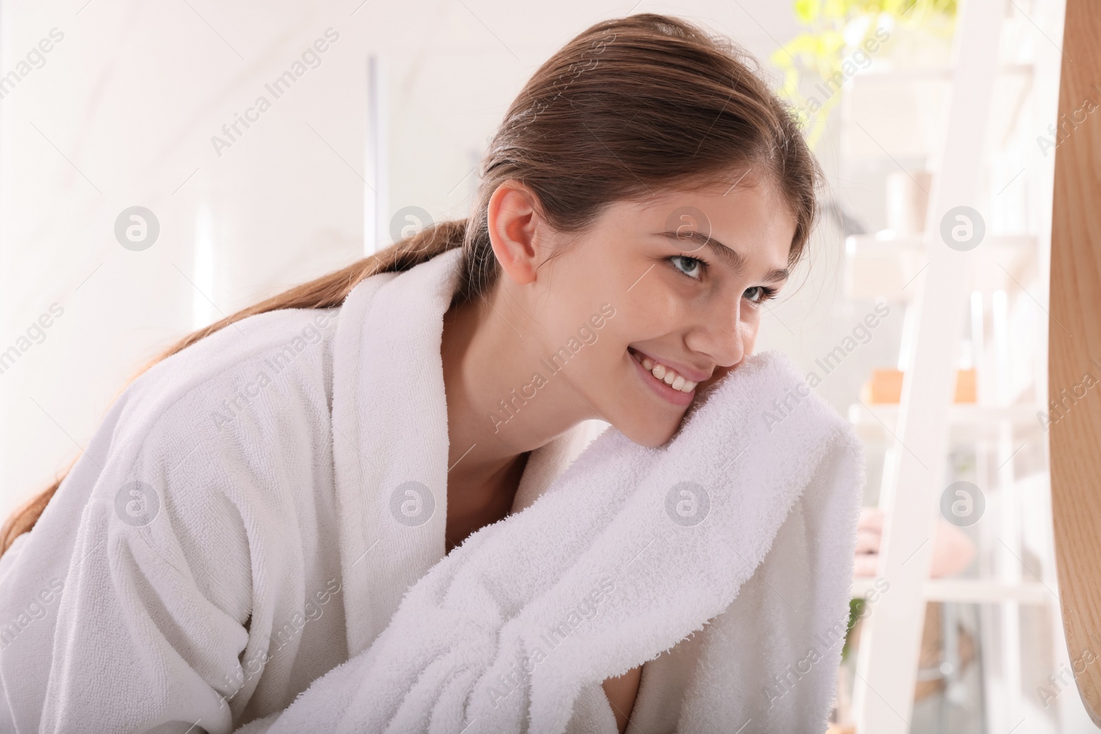 Photo of Beautiful teenage girl wiping face with towel in bathroom