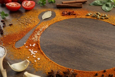 Silhouettes of spoon and plate made with spices and ingredients on wooden table